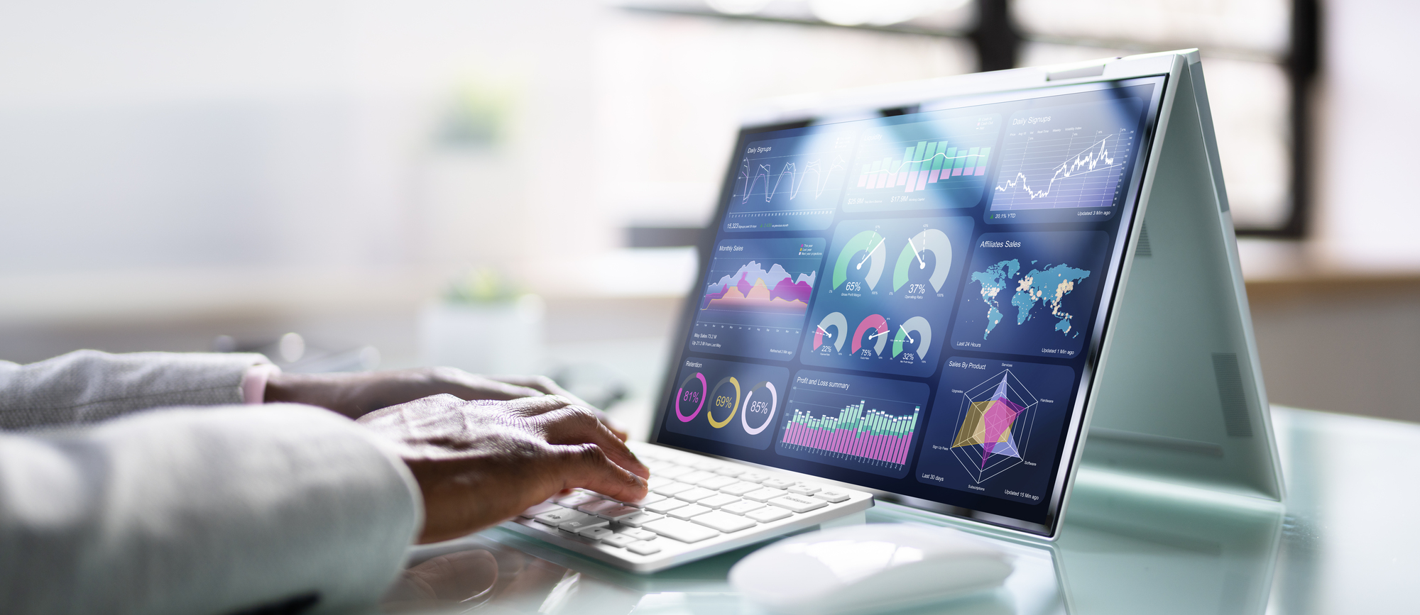 Person works on laptop with dashboard full of data visualizations, graphs and KPI gauges on the screen.