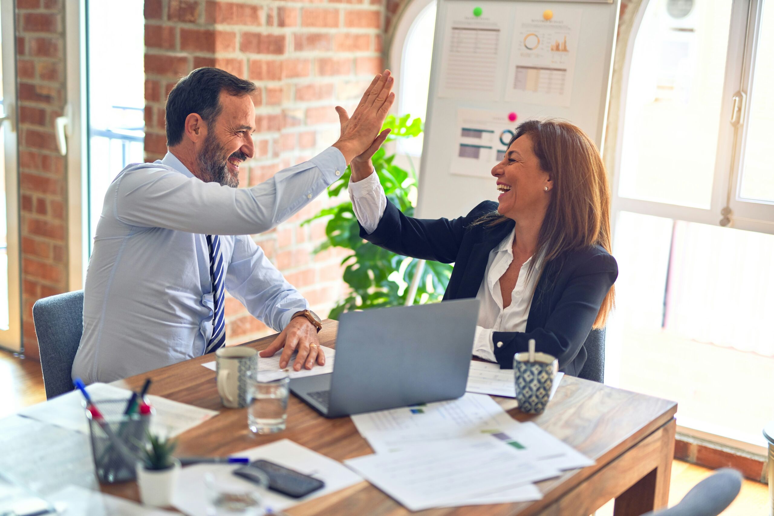 a man and a woman sit at a table and give each other a high five