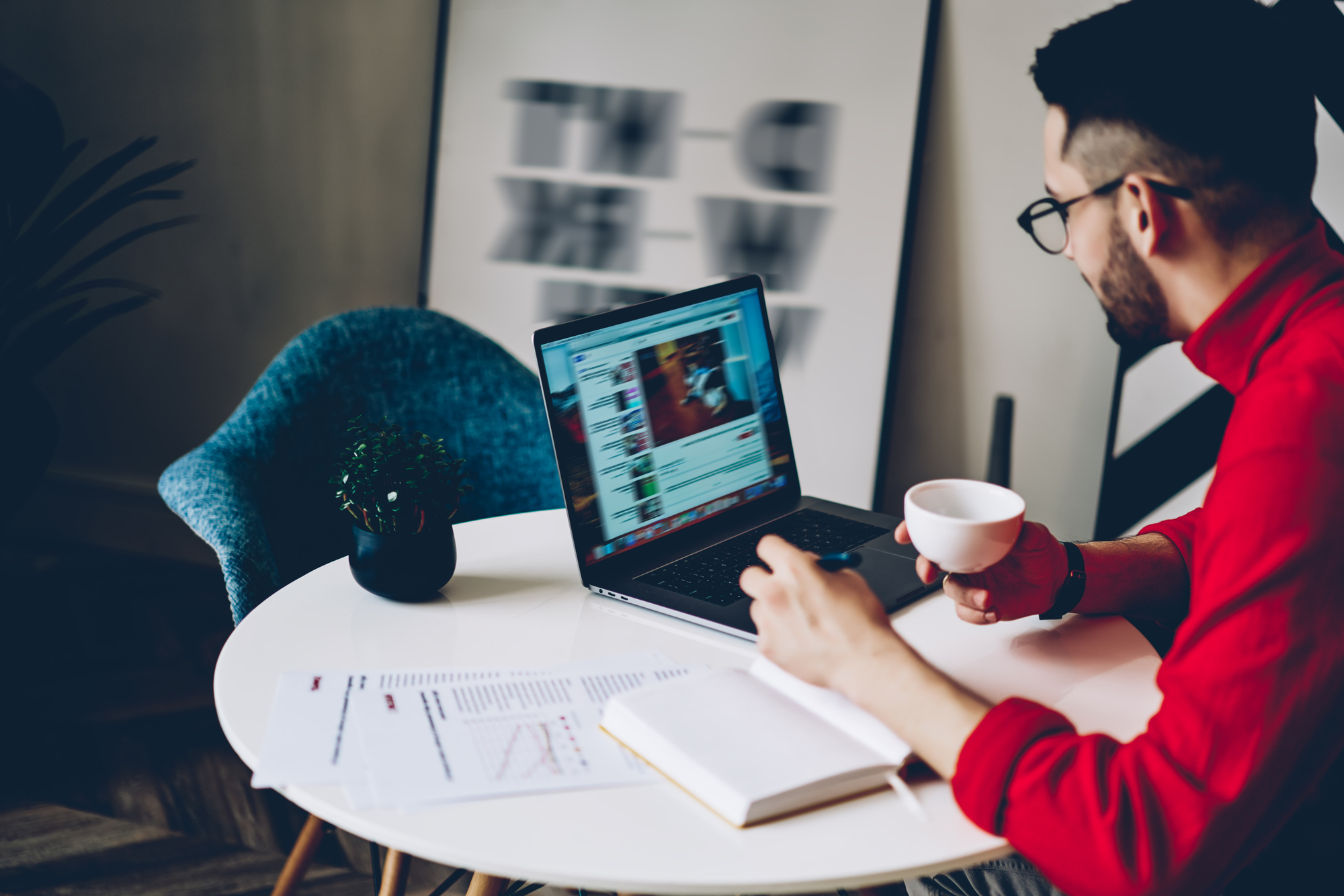 man in red sweater watches video on laptop