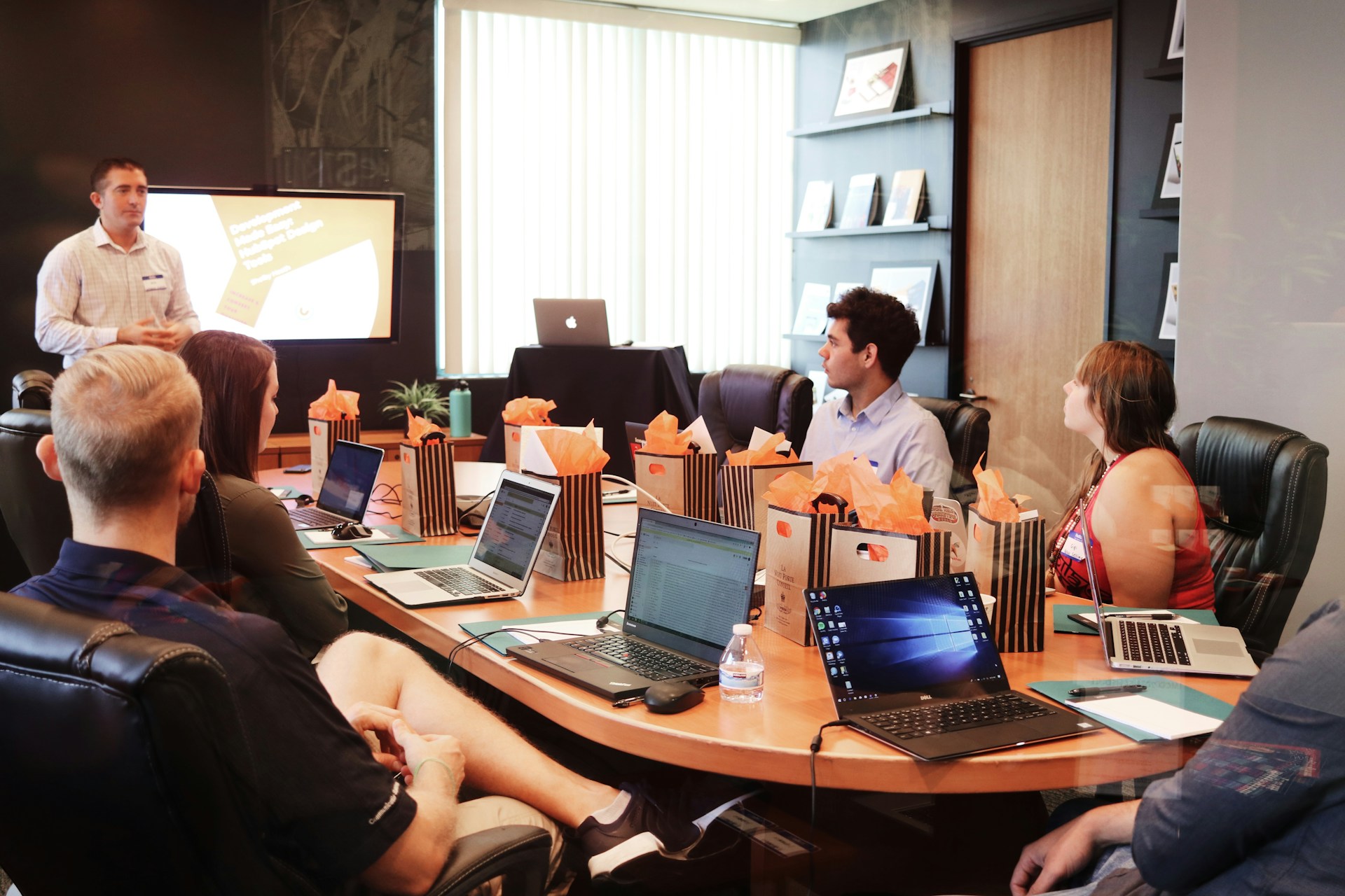 a group of people around a table listening to a speaker