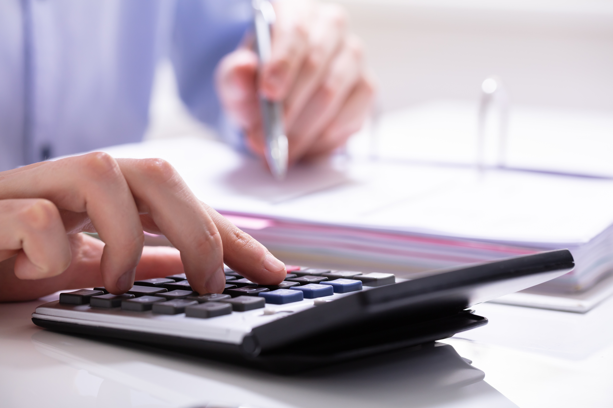 man in blue blouse types on calculator